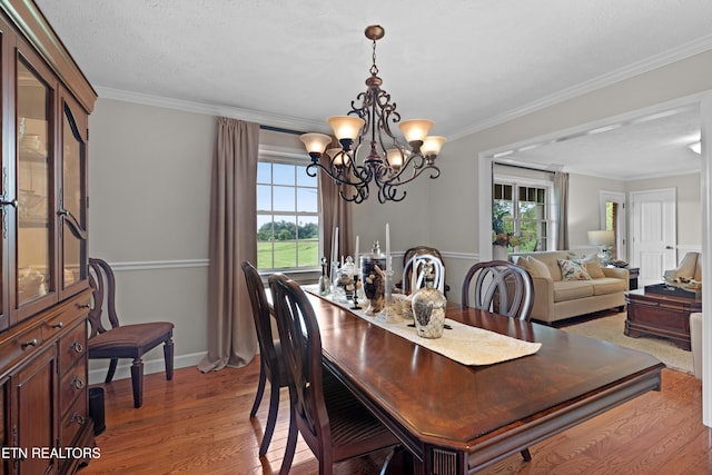 dining area with light hardwood / wood-style flooring, ornamental molding, a healthy amount of sunlight, and a textured ceiling