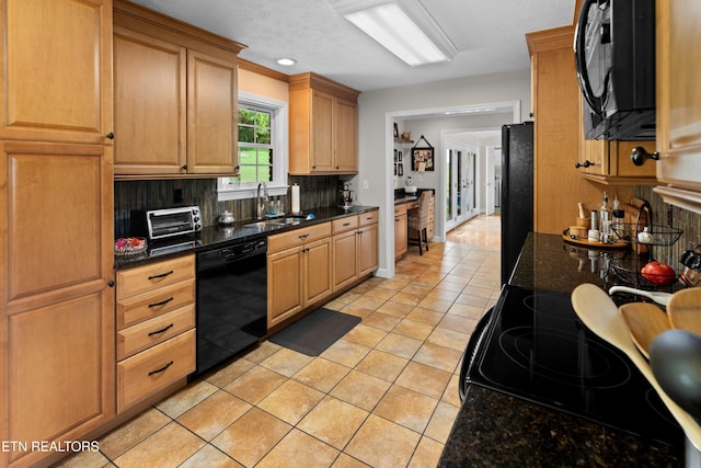 kitchen with backsplash, dark stone counters, sink, black appliances, and light tile patterned floors