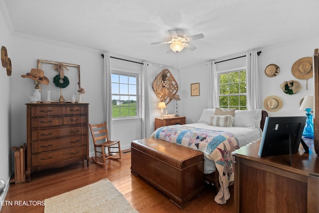 bedroom featuring crown molding, light hardwood / wood-style flooring, multiple windows, and ceiling fan