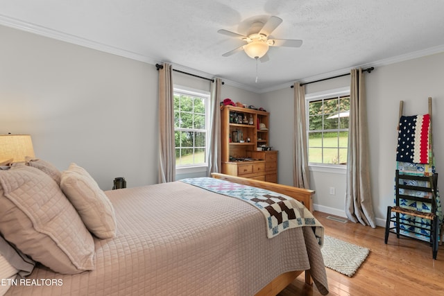 bedroom with light hardwood / wood-style flooring, ornamental molding, multiple windows, and ceiling fan