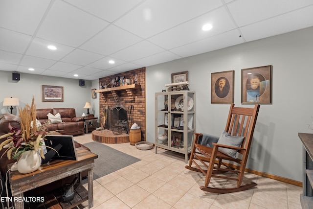 tiled living room with a paneled ceiling and a fireplace