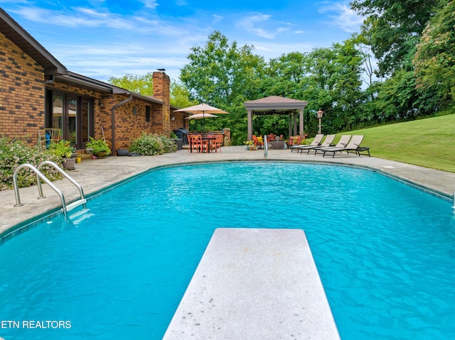 view of swimming pool featuring a diving board, a patio area, and a lawn