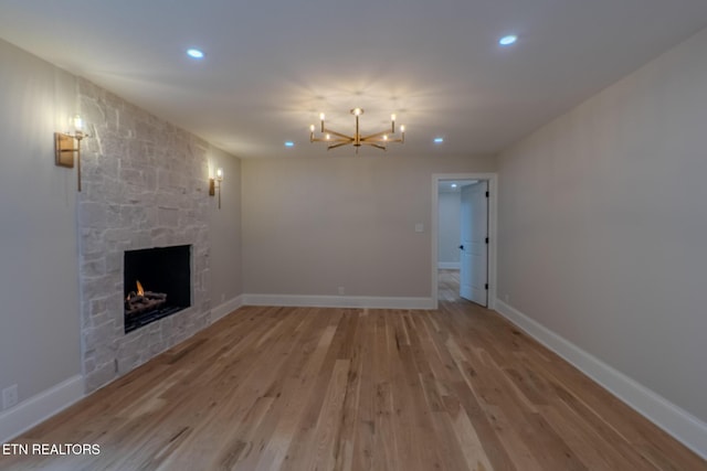 unfurnished living room with a chandelier, a fireplace, recessed lighting, light wood-style flooring, and baseboards