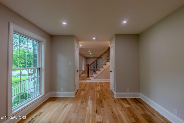 spare room featuring healthy amount of natural light, stairway, light wood-type flooring, baseboards, and recessed lighting