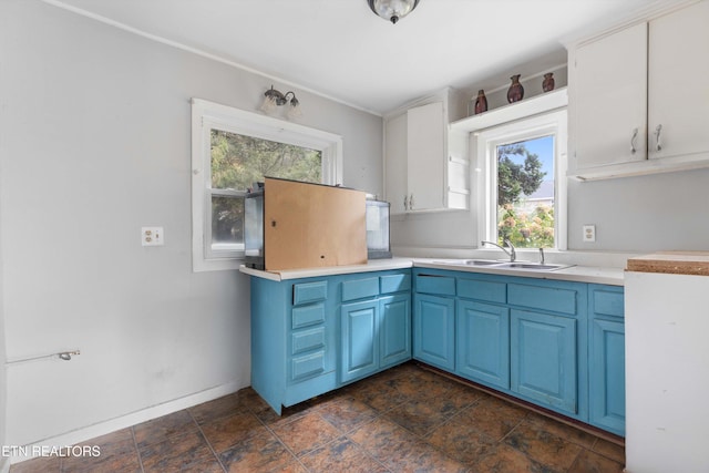 kitchen with white cabinetry, blue cabinetry, and sink