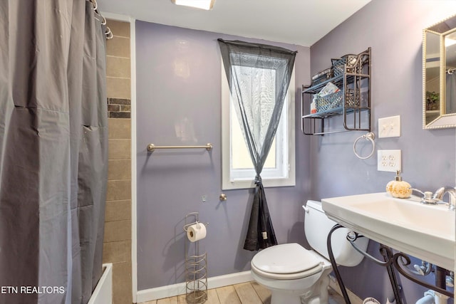 bathroom with hardwood / wood-style floors, shower / tub combo, and toilet