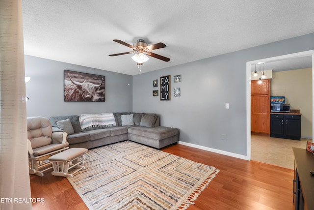 living room with ceiling fan, a textured ceiling, and hardwood / wood-style floors