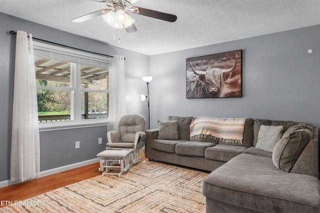 living room with a textured ceiling, light wood-type flooring, and ceiling fan