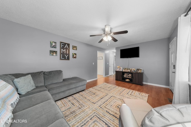 living room with ceiling fan, wood-type flooring, and a textured ceiling