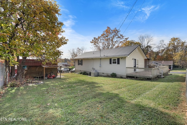 rear view of property featuring a storage unit, a deck, and a lawn