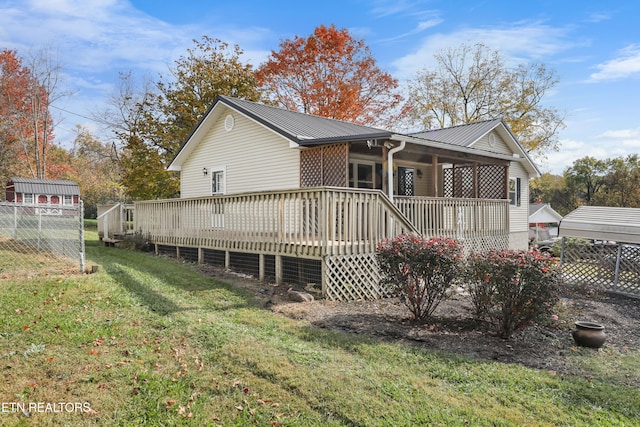 rear view of property with a wooden deck and a yard