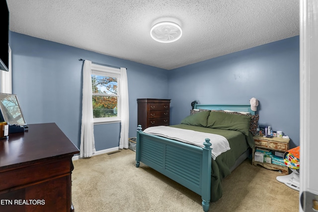 bedroom featuring a textured ceiling and light colored carpet