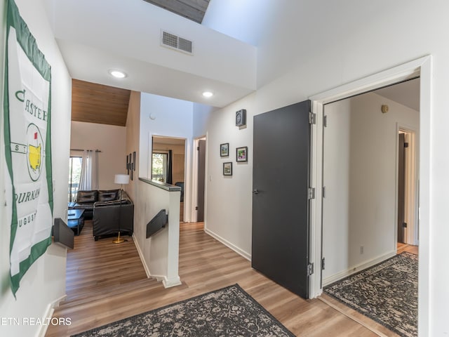 hall featuring light hardwood / wood-style floors and vaulted ceiling