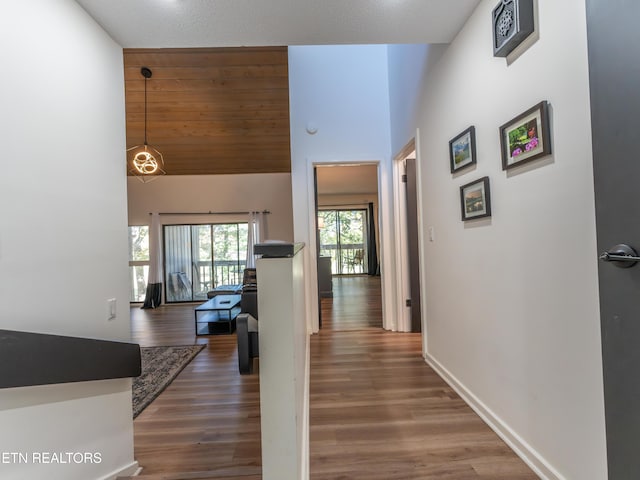 corridor with a textured ceiling, dark hardwood / wood-style floors, and high vaulted ceiling