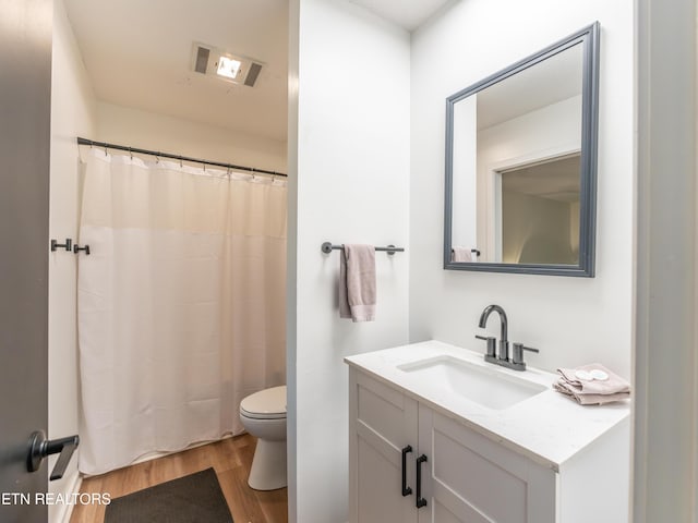 bathroom featuring vanity, toilet, hardwood / wood-style flooring, and walk in shower