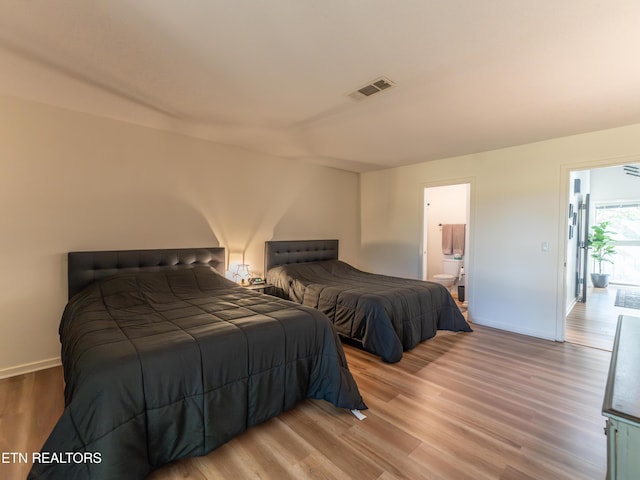 bedroom with light wood-type flooring and ensuite bath