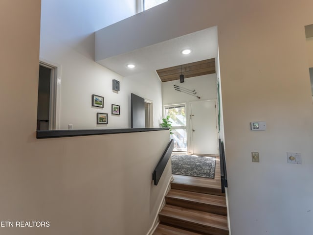 staircase with hardwood / wood-style floors, lofted ceiling with beams, and a textured ceiling