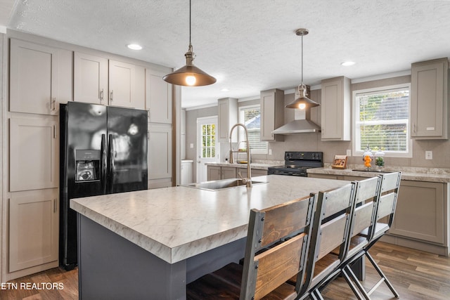 kitchen with sink, black appliances, an island with sink, and a healthy amount of sunlight