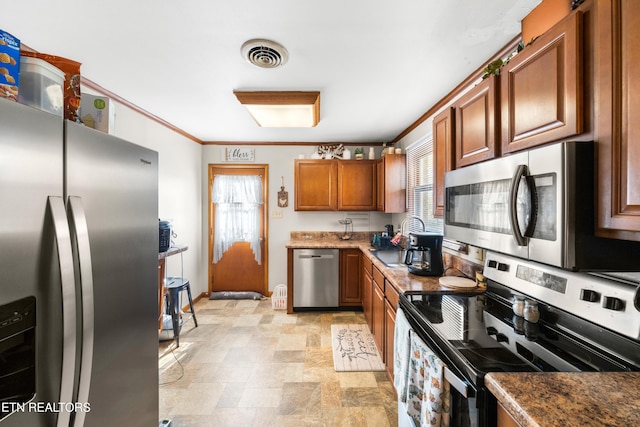 kitchen featuring crown molding, dark stone counters, and appliances with stainless steel finishes