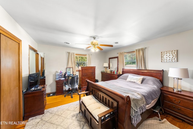 bedroom featuring light wood-type flooring, ceiling fan, a closet, and multiple windows