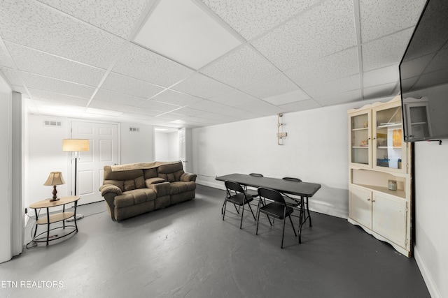 dining space with concrete flooring and a paneled ceiling