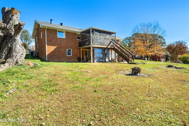 rear view of house featuring a fire pit, cooling unit, a yard, and a sunroom