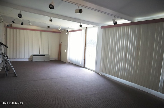 carpeted spare room with beam ceiling and track lighting