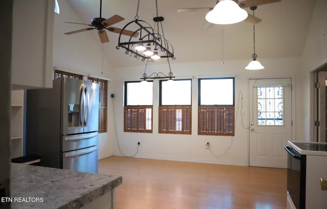 kitchen with light hardwood / wood-style floors, hanging light fixtures, stainless steel appliances, and high vaulted ceiling