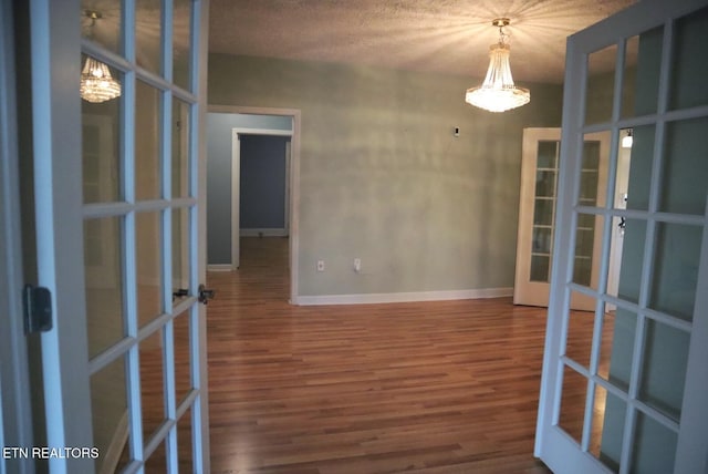 empty room featuring french doors, a textured ceiling, and hardwood / wood-style floors