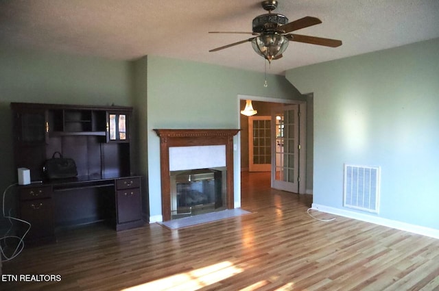 unfurnished living room with a textured ceiling, hardwood / wood-style flooring, and ceiling fan