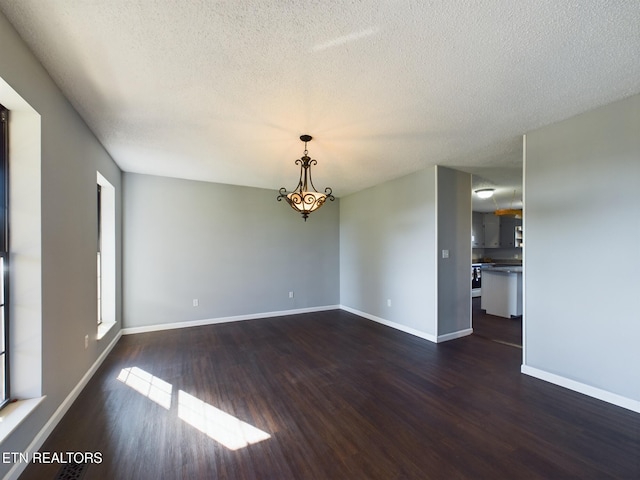 spare room with a textured ceiling and dark hardwood / wood-style floors