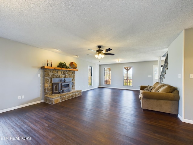 unfurnished living room with a wood stove, a textured ceiling, dark wood-type flooring, and ceiling fan