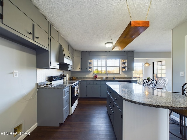 kitchen with range hood, white range with electric stovetop, a kitchen bar, a textured ceiling, and dark hardwood / wood-style flooring