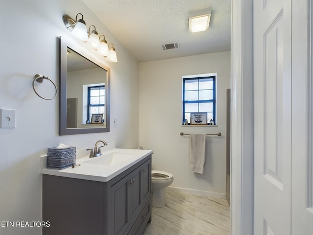 bathroom with vanity, toilet, and a textured ceiling