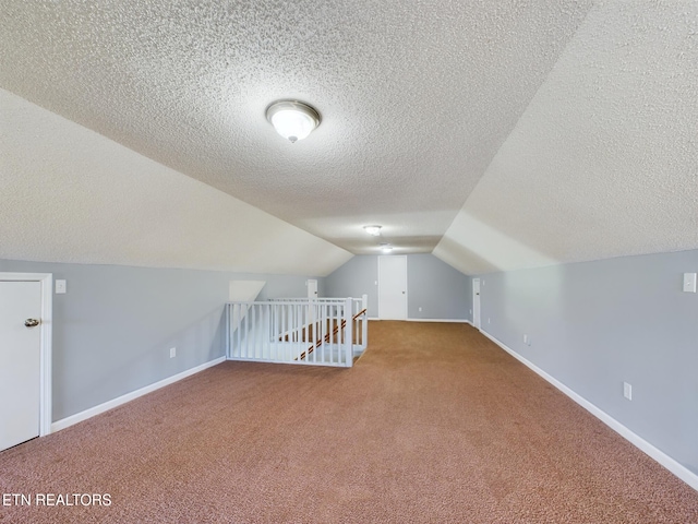 additional living space featuring lofted ceiling, a textured ceiling, and carpet floors