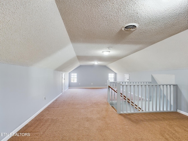 bonus room featuring a textured ceiling, carpet flooring, and lofted ceiling