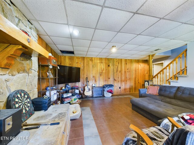 living room with a paneled ceiling and wooden walls