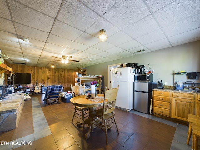 dining area with sink, wooden walls, a paneled ceiling, and ceiling fan