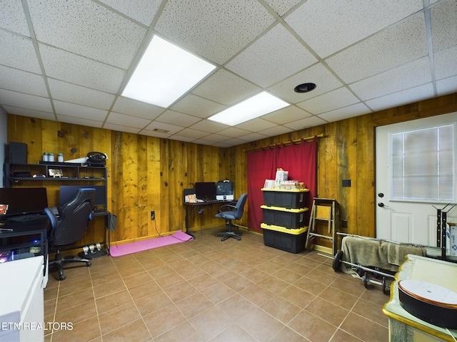 office space with a paneled ceiling and wood walls