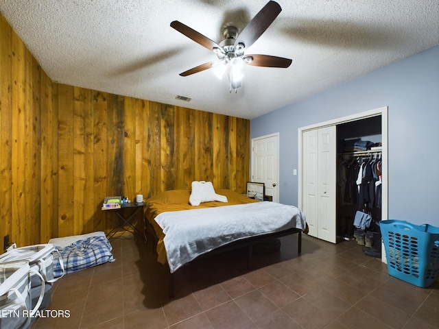 tiled bedroom with ceiling fan, a textured ceiling, and wooden walls