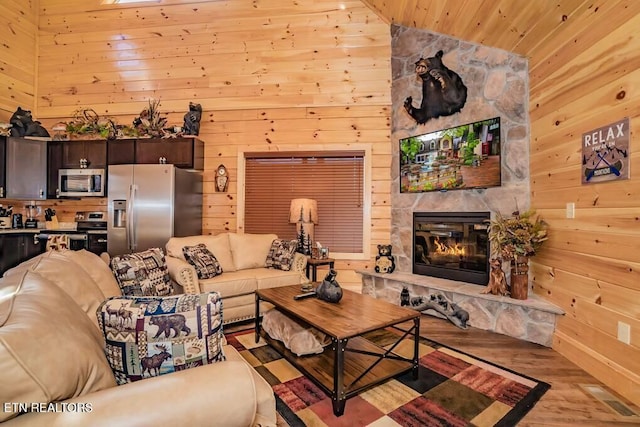 living room featuring wooden walls, a fireplace, light hardwood / wood-style floors, and wooden ceiling