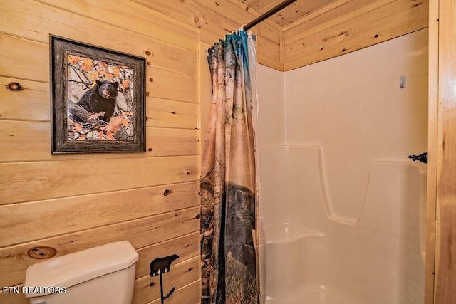 bathroom with toilet, wooden walls, and a shower with shower curtain