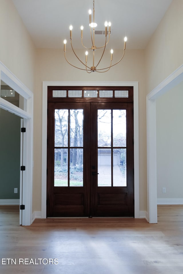 foyer entrance featuring a chandelier, light wood-type flooring, and french doors