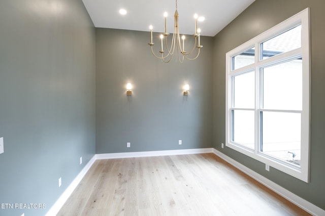 unfurnished room featuring light wood-type flooring and a notable chandelier