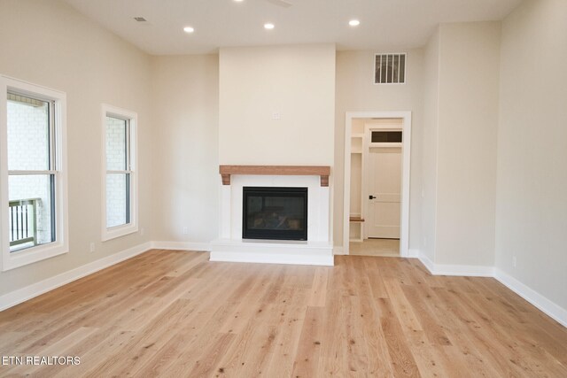 unfurnished living room featuring a high ceiling and light hardwood / wood-style floors