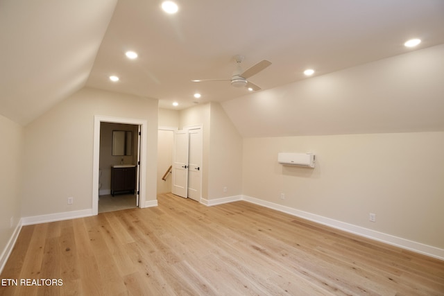 bonus room with light wood-type flooring, vaulted ceiling, ceiling fan, and a wall unit AC