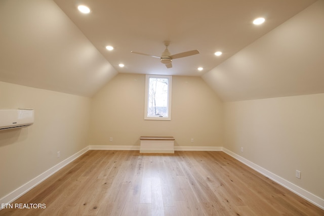 bonus room with light wood-type flooring, vaulted ceiling, ceiling fan, and a wall unit AC