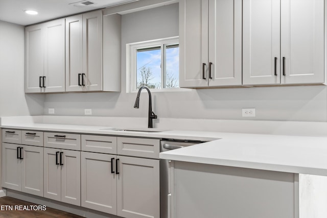 kitchen featuring dark hardwood / wood-style flooring, sink, white cabinets, and stainless steel dishwasher