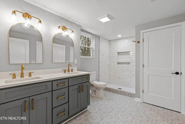 bathroom with tiled shower, vanity, toilet, and tile patterned flooring