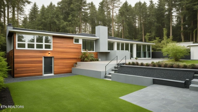 back of house featuring a sunroom, a patio area, and a lawn